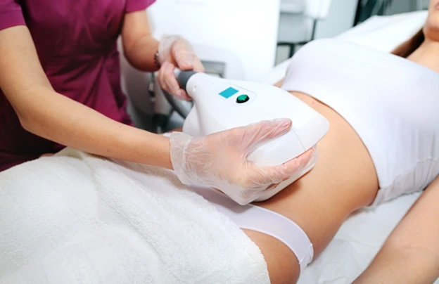 Professional administering non-surgical body sculpting treatment on patient's abdomen.