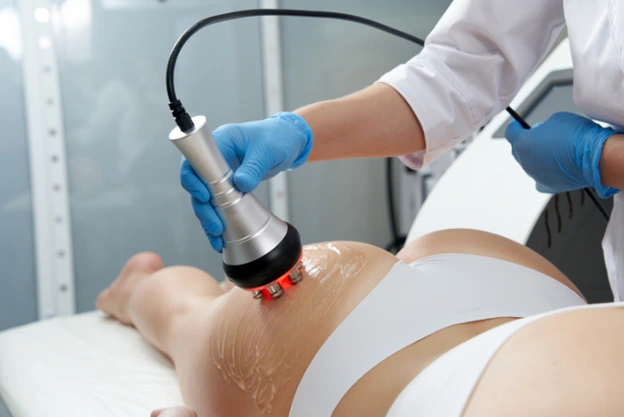 Healthcare professional applying radiofrequency device for body contouring treatment on patient's thigh.