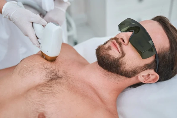 Man receiving laser hair removal treatment on his chest at a professional clinic.