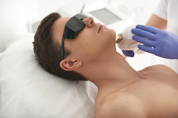 Man receiving laser hair removal treatment on his jawline at a professional clinic.